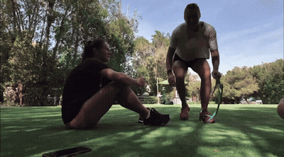 A Man And A Woman Sitting On The Grass Talking GIF