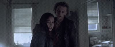 A Man And A Woman Standing In A Dark Room GIF