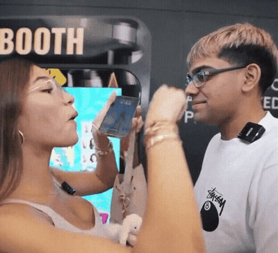 A Man And A Woman Standing In Front Of A Booth GIF