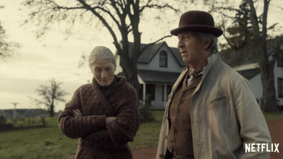 A Man And A Woman Standing In Front Of A House With A Netflix Logo On The Bottom GIF