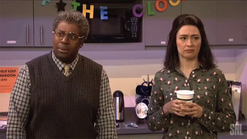 A Man And A Woman Standing In Front Of A Sign That Says The Clock On It GIF