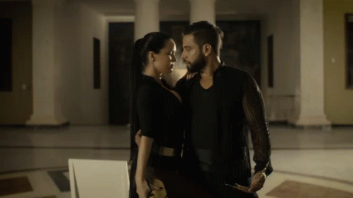 A Man And A Woman Standing Next To Each Other In A Dark Room GIF