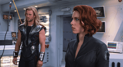 A Man And A Woman Standing Next To Each Other In A Room GIF
