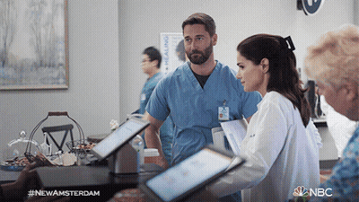 A Man And A Woman Standing Next To Each Other In A Room With Nbc Written In The Corner GIF