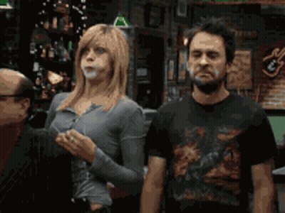 A Man And A Woman Standing Next To Each Other In Front Of A Bar GIF