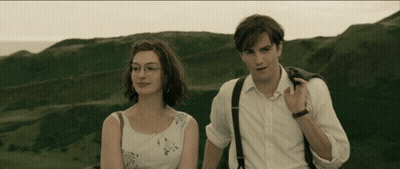 A Man And A Woman Standing Next To Each Other In Front Of A Mountain GIF