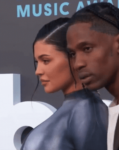 A Man And A Woman Standing Next To Each Other In Front Of A Music Awards Sign GIF