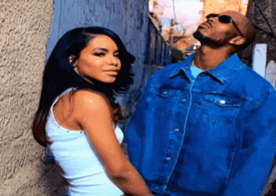 A Man And A Woman Standing Next To Each Other In Front Of A Wall GIF