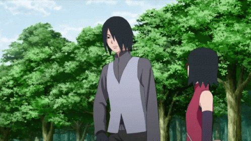 A Man And A Woman Standing Next To Each Other In Front Of Trees GIF