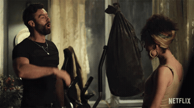 A Man And A Woman Standing Next To Each Other With A Netflix Logo In The Corner GIF