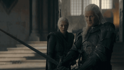 A Man And A Woman Standing Next To Each Other With Swords GIF
