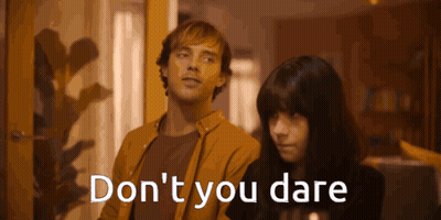 A Man And A Woman Standing Next To Each Other With The Words " Do N't You Dare " Written On The Screen GIF