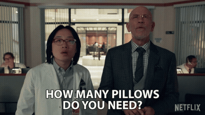 A Man And A Woman Standing Next To Each Other With The Words How Many Pillows Do You Need On The Bottom GIF