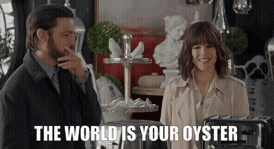 A Man And A Woman Standing Next To Each Other With The Words " The World Is Your Oyster " Behind Them GIF
