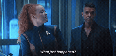 A Man And A Woman Standing Next To Each Other With The Words What Just Happened Written On The Bottom GIF