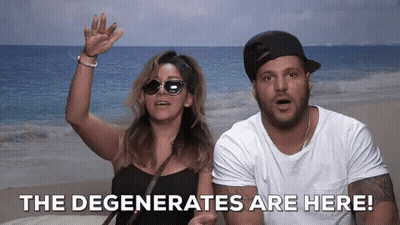 A Man And A Woman Standing On A Beach With The Words " The Degenerates Are Here " Behind Them GIF