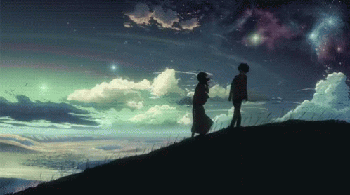 A Man And A Woman Standing On Top Of A Hill Holding Hands GIF