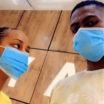 A Man And A Woman Wearing Blue Face Masks Looking At Each Other GIF