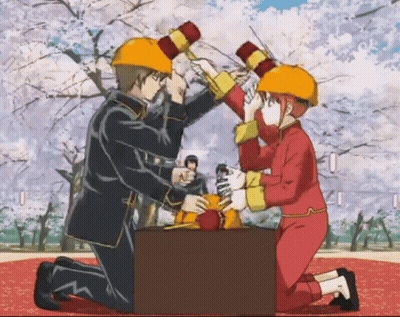 A Man And A Woman Wearing Hard Hats Are Holding Hammers GIF