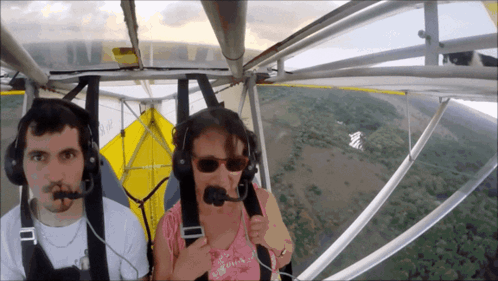A Man And A Woman Wearing Headphones Are Flying A Small Plane GIF