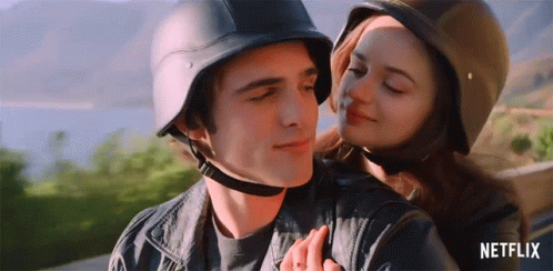 A Man And A Woman Wearing Helmets Are Hugging . GIF