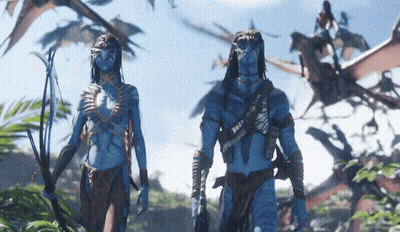 A Man And A Woman With Blue Faces Are Standing In A Forest GIF