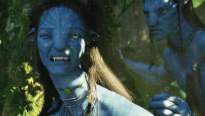 A Man And A Woman With Blue Faces Are Standing In A Forest GIF