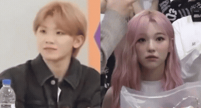 A Man And A Woman With Pink Hair Are Sitting Next To Each Other And Looking At The Camera . GIF