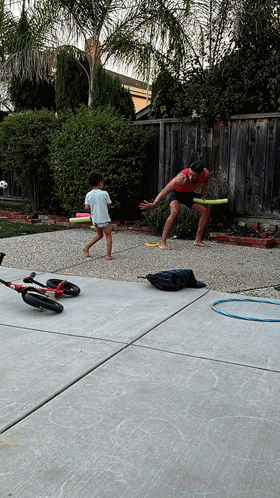 A Man And Child Are Playing Frisbee In A Backyard GIF