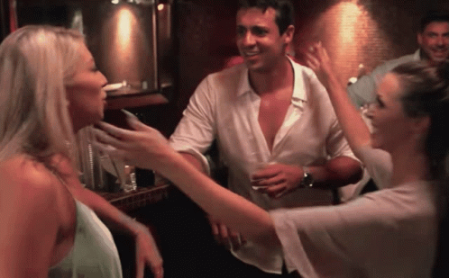 A Man And Two Women Are Dancing In A Bar GIF