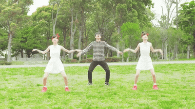 A Man And Two Women Are Dancing In A Park With Trees In The Background GIF