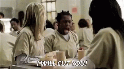 A Man And Two Women Are Sitting At A Table In A Jail Cell Talking To Each Other . GIF