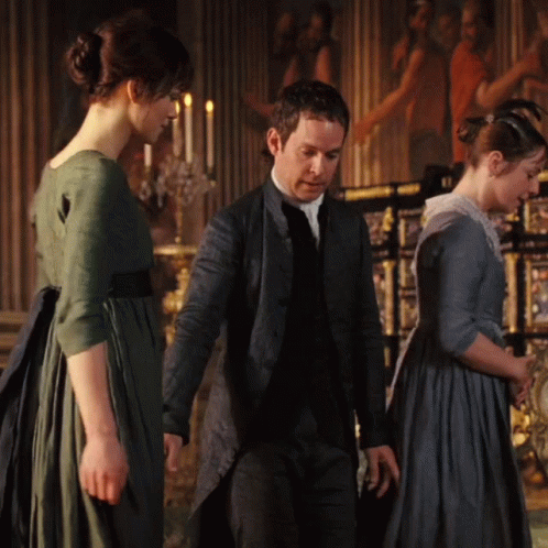 A Man And Two Women Are Standing In A Room With Candles In The Background GIF