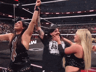 A Man And Two Women Are Standing In A Wrestling Ring With A Man Wearing A Shirt That Says Wwe On It GIF