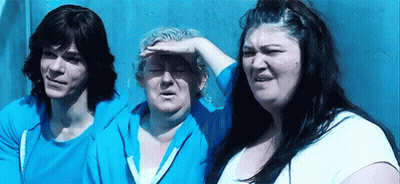 A Man And Two Women Are Standing Next To Each Other In Front Of A Wall . GIF