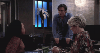 A Man And Two Women Sit At A Table In A Restaurant Talking GIF
