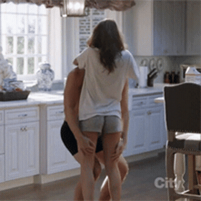 A Man And Woman Are Dancing In A Kitchen With A City Logo On The Bottom GIF