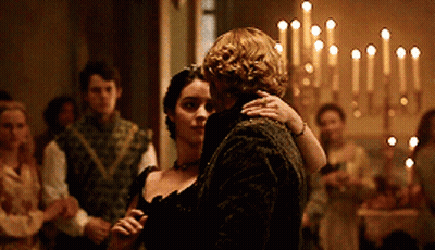 A Man And Woman Are Dancing In A Room With Candles In The Background GIF