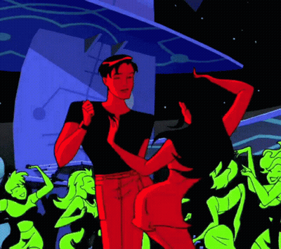 A Man And Woman Are Dancing In Front Of A Crowd Of Green Women GIF