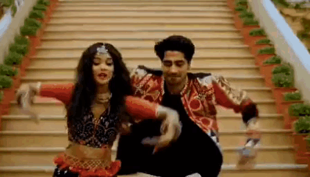 A Man And Woman Are Dancing On A Set Of Stairs . GIF