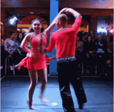 A Man And Woman Are Dancing On A Stage In Front Of A Crowd GIF