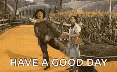 A Man And Woman Are Dancing On A Yellow Brick Road . GIF