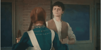 A Man And Woman Are Dancing Together In Front Of A Brick Wall . GIF