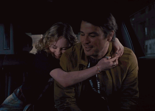 A Man And Woman Are Holding Hands In A Car GIF