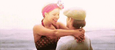A Man And Woman Are Hugging Each Other On The Beach . GIF