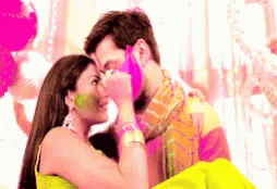 A Man And Woman Are Kissing And The Woman Is Covering The Man 'S Face With Holi Paint GIF