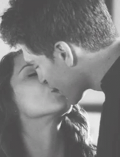 A Man And Woman Are Kissing In A Black And White Photo GIF