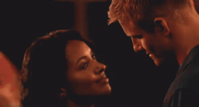 A Man And Woman Are Kissing In A Crowded Room GIF