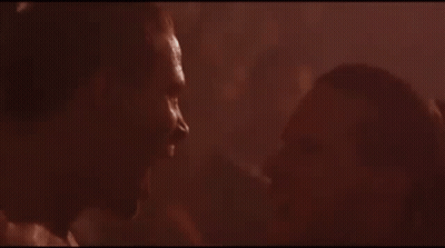 A Man And Woman Are Kissing In A Dark Room In A Movie . GIF