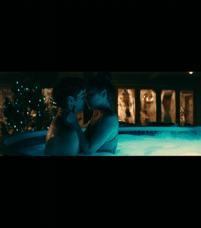 A Man And Woman Are Kissing In A Hot Tub At Night GIF